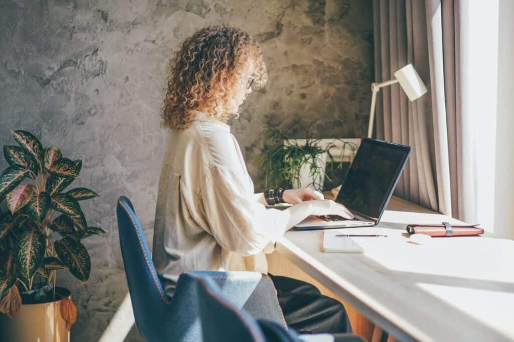 Woman in eyeglasses working at home using laptop, female working in modern studio.